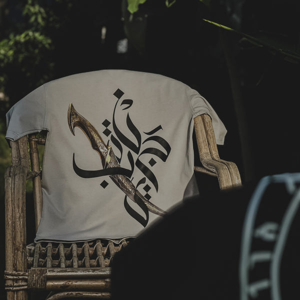 White t-shirt with Arabic calligraphy on a wooden chair outdoors