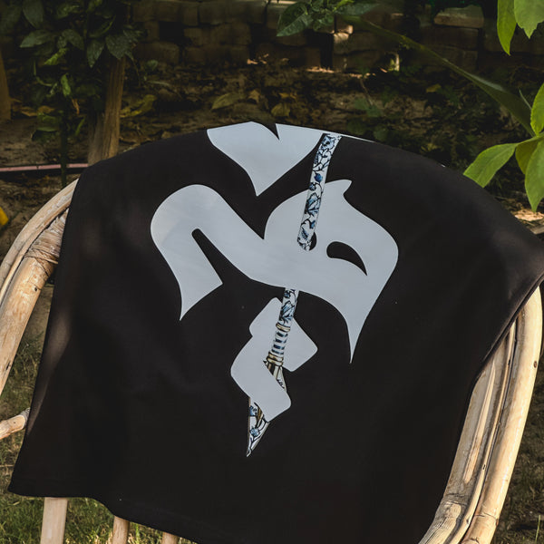 Black fabric with a white symbol and chain draped over a chair outdoors.