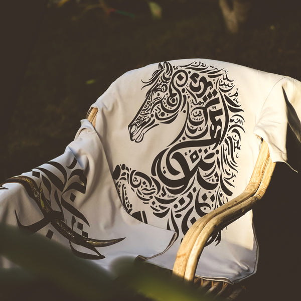 Beige t-shirt with black tribal horse design on a chair against a dark background