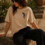 QADIM Safar Graphic Tee worn outdoors on stone steps, Cairo streetwear lifestyle