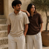 Two people wearing matching polo shirts and pants standing outdoors.