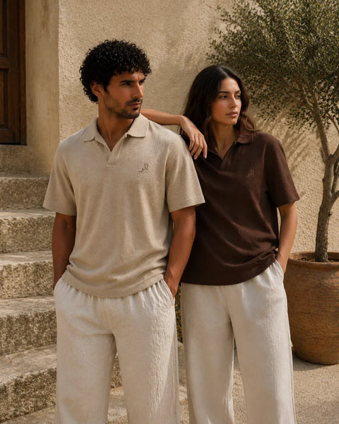 Two people wearing matching polo shirts and pants standing outdoors.