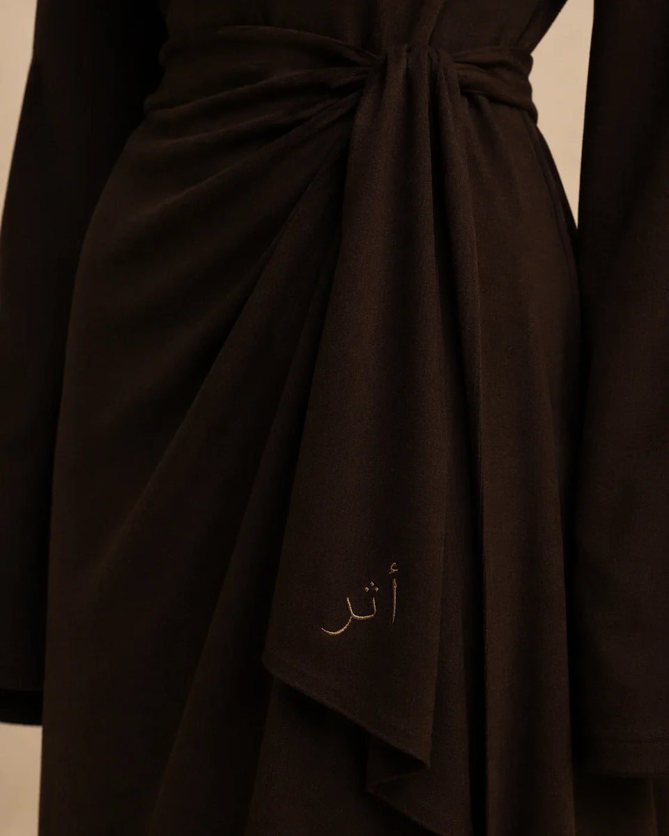 Brown fabric with Arabic text embroidery on a neutral background