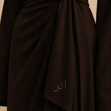 Brown fabric with Arabic text embroidery on a neutral background