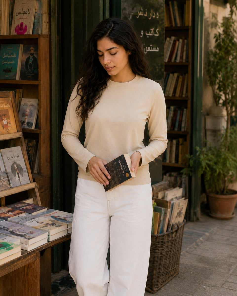 QADIM washed beige long sleeve tee at a heritage Arabic bookshop, editorial look