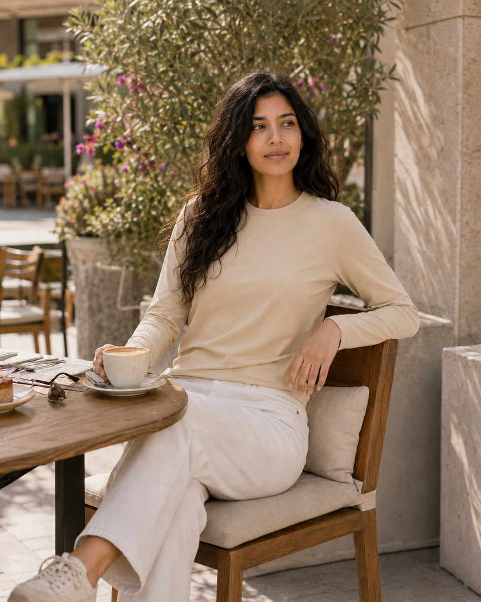 QADIM washed beige long sleeve tee, seated cafe editorial in warm tones