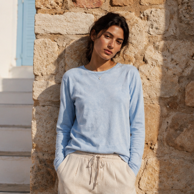 QADIM washed baby blue long sleeve tee front view against stone wall