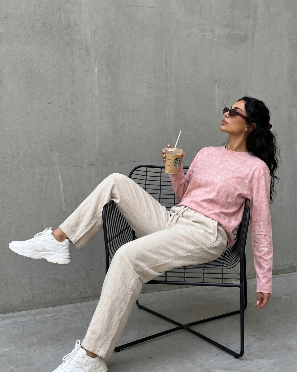 Model in QADIM washed pink long sleeve tee with cream trousers, outdoor editorial look