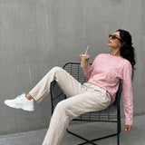 Model in QADIM washed pink long sleeve tee with cream trousers, outdoor editorial look