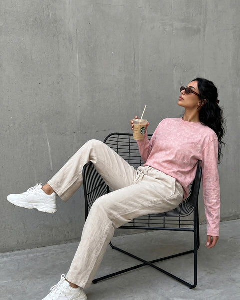 Model in QADIM washed pink long sleeve tee with cream trousers, outdoor editorial look