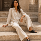 Woman in ATHAR Linen Relaxed Fit Off White shirt sitting on heritage stone steps | امرأة بقميص أثر الكتان الفضفاض أوف وايت جالسة على سلم حجري أثري