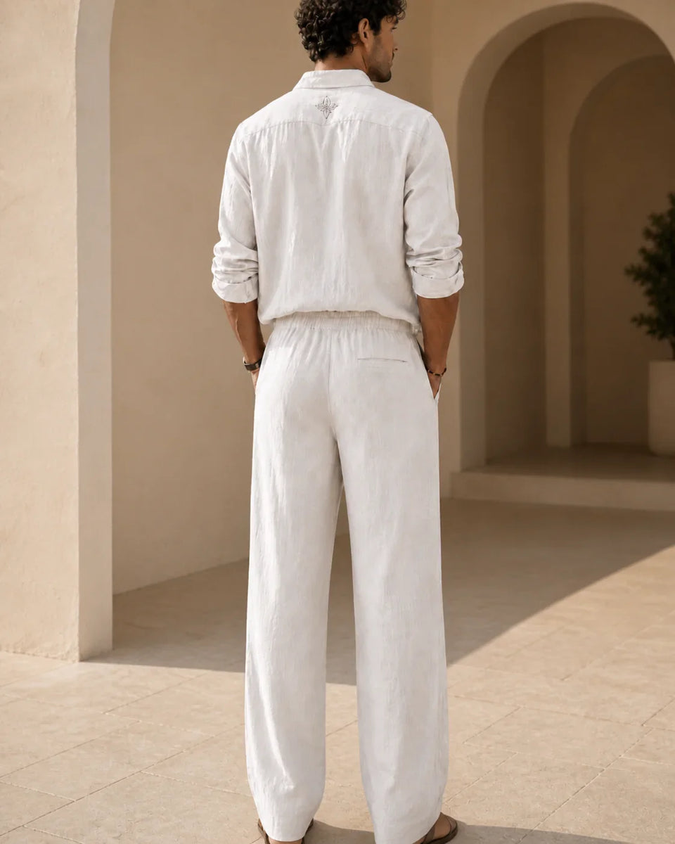 Back view of QADIM off-white linen trousers with matching linen shirt and subtle embroidered neck symbol