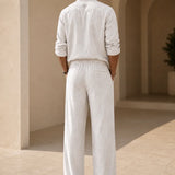 Back view of QADIM off-white linen trousers with matching linen shirt and subtle embroidered neck symbol