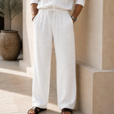 Front detail of QADIM off-white linen trousers showing drawstring waistband and wide-leg fit