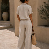 Back view of QADIM sand linen trousers styled on female model in warm courtyard setting