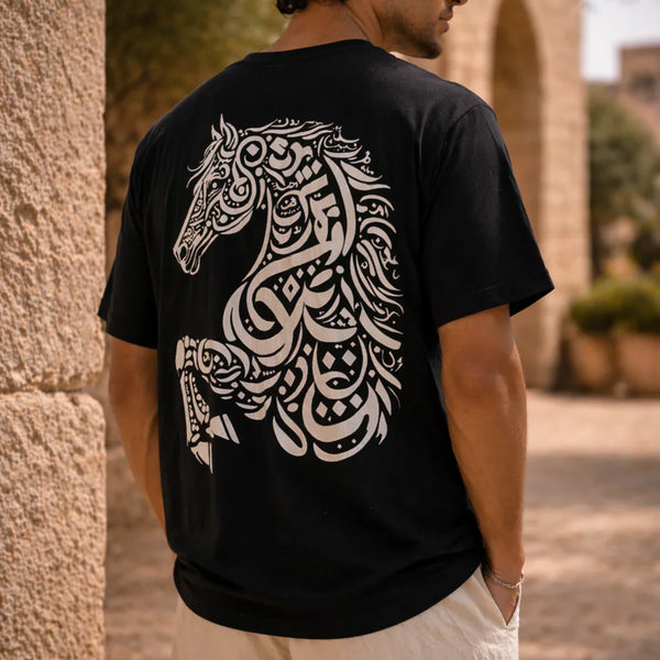 Man wearing a black t-shirt with a white horse design on the back, standing against a stone wall.