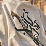 Close-up of Jambiya dagger and Arabic calligraphy graphic print on QADIM Beige t-shirt