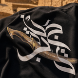 Close-up of Jambiya dagger and Arabic calligraphy graphic print on QADIM Black t-shirt