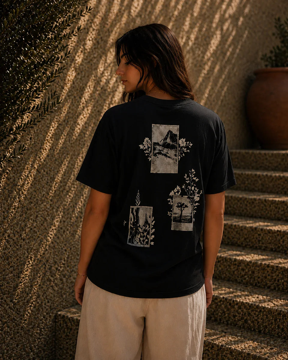 QADIM Naqsh black half sleeve tee back graphic worn by female model in warm textured stone setting