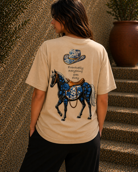 Person wearing a beige t-shirt with a blue horse and cowboy hat design.