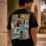 Person wearing a black t-shirt with vintage stamp designs on the back, standing outdoors.