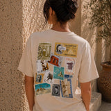 Person wearing a white t-shirt with vintage-style graphic on the back, standing against a textured wall.