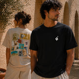 Two people standing outdoors with a man wearing a black t-shirt with a logo and a woman wearing a white t-shirt with a graphic design.