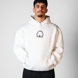 QADIM Asil relaxed hoodie in white, front emblem, worn by male model | هودي الأصيل ريلاكس أبيض من قدّام