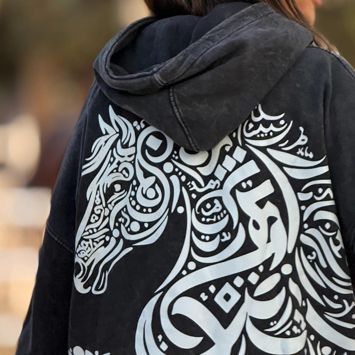 QADIM Asil washed hoodie in black, calligraphy horse back print — worn by @marwaabuelezz | هودي أصيل مغسول أسود