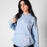 QADIM Jambiya washed hoodie in baby blue, three-dagger front emblem, female model | هودي جنبية مغسول بيبي بلو من قدّام